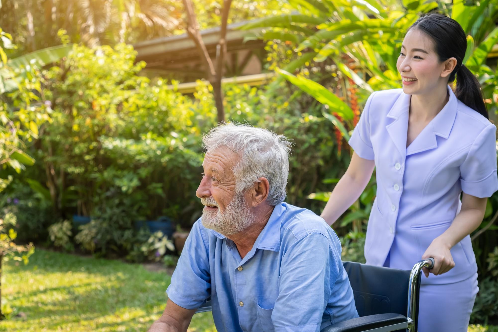 medicial tourism asia nurse take care elderly man wheelchair garden
