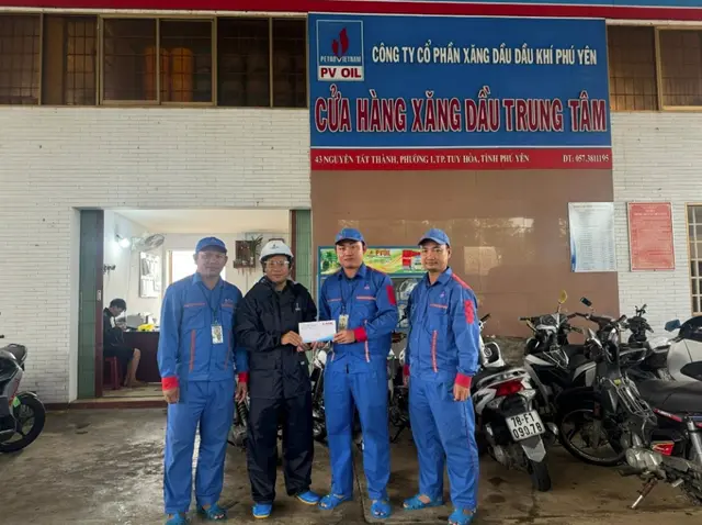 Ông Trần Văn Hay - Phó giám đốc, Chủ tịch Công đoàn PVOIL Phú Yên trao thưởng cho anh Nguyễn Duy Luân - nhân viên CHXD Trung Tâm (người mặc đồng phục xanh đứng giữa) đã có hành động dũng cảm cứu người.  Ảnh: Tinnhanhchungkhoan.vn